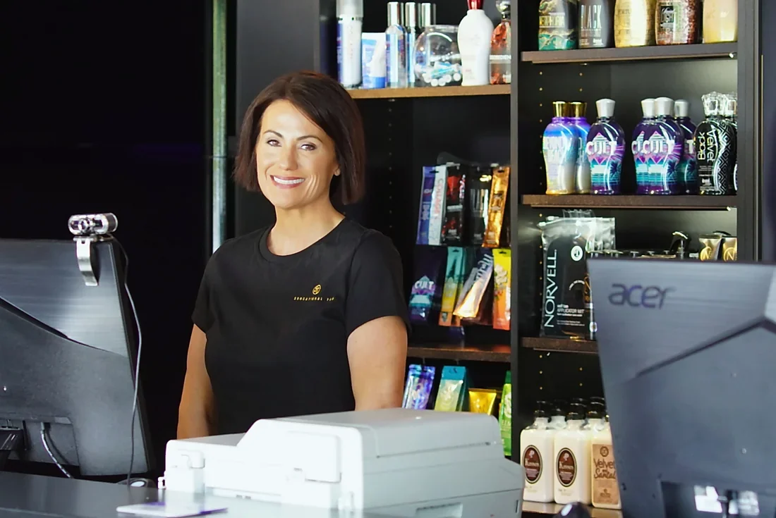 A friendly Sunsational Tan team member welcoming guests at the front desk